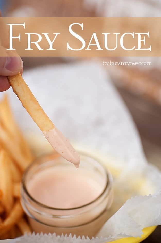 A woman dipping a french fry into a jar of fry sauce.