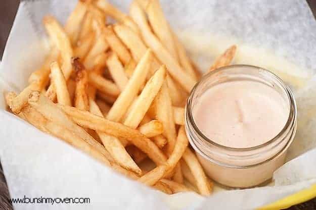 A pile of french fries next to a jar of fry sauce.