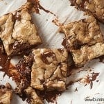 Dark chocolate cookie bars spread out on a cutting board.