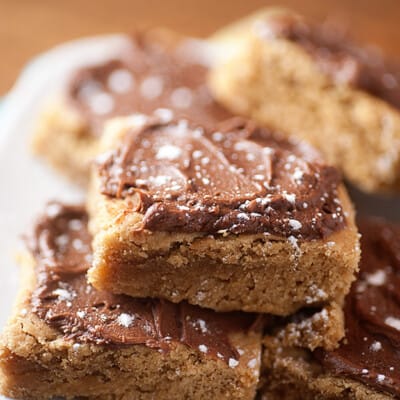 A close up of fudge frosted peanut butter bars in a pile.