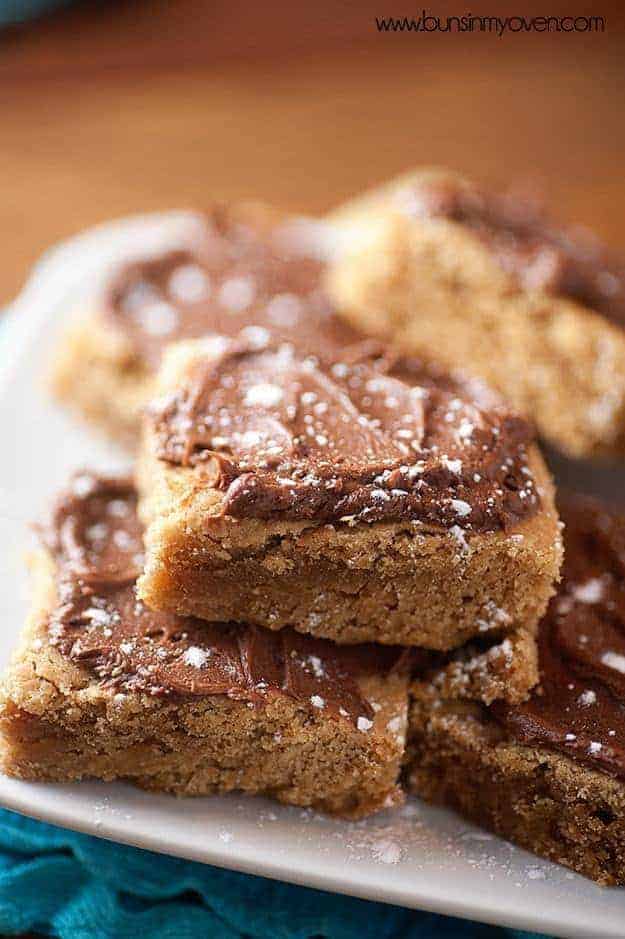 A close up of fudge frosted peanut butter bars in a pile.