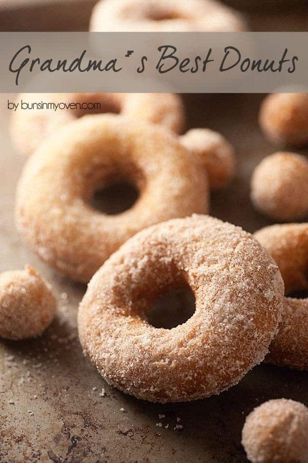 Fried donuts and donut holes on a baking sheet.