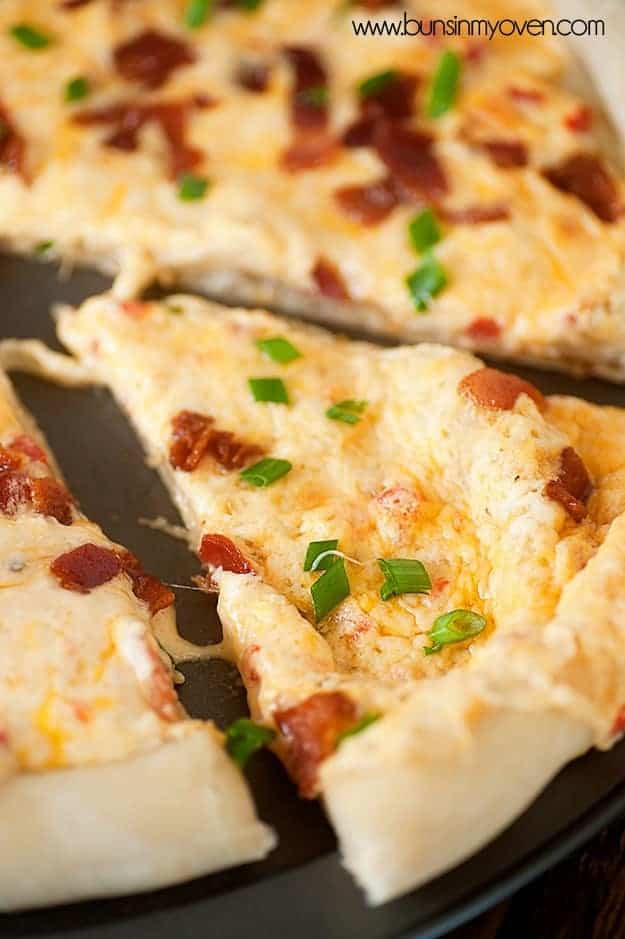 A slice of bacon and cheese pizza up close.