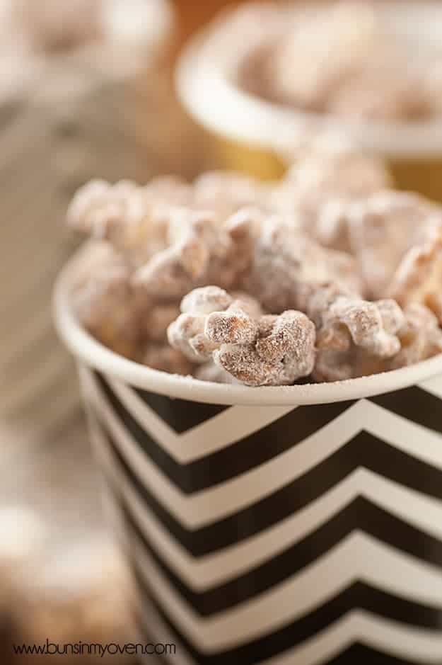 A close up of powdered sugar popcorn sticking out of the top of a paper cup.