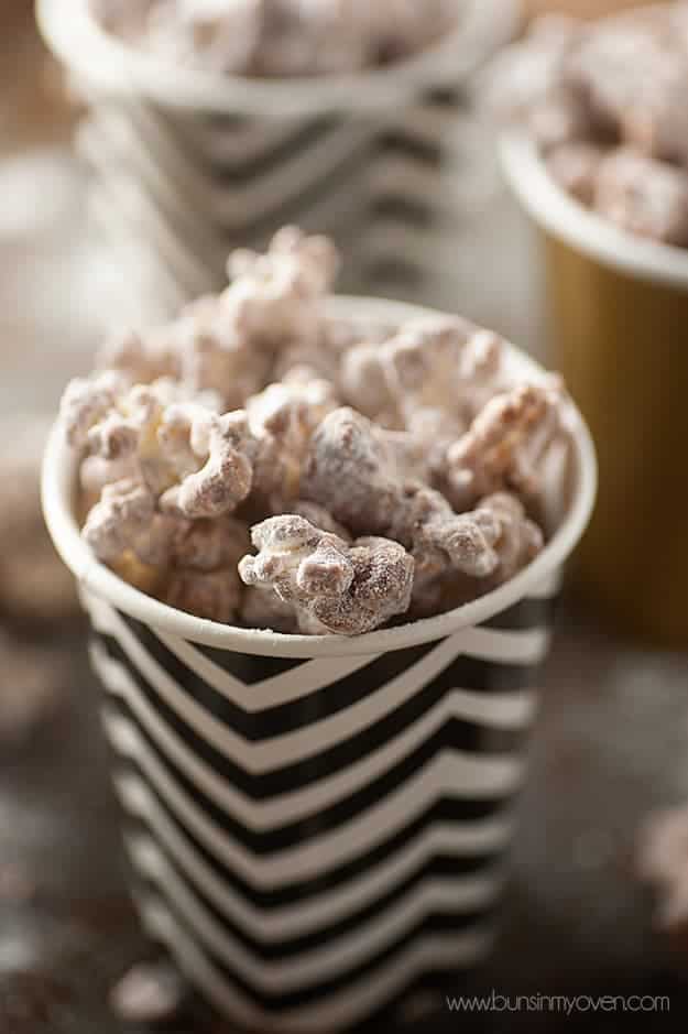 A close up of powdered sugar popcorn in a black and white cup.