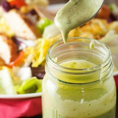 Avocado salad dressing in a glass jar with a spoonful above it.