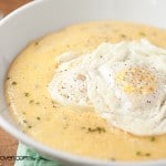 A close up of a bowl of grits with two fried eggs on top of it.