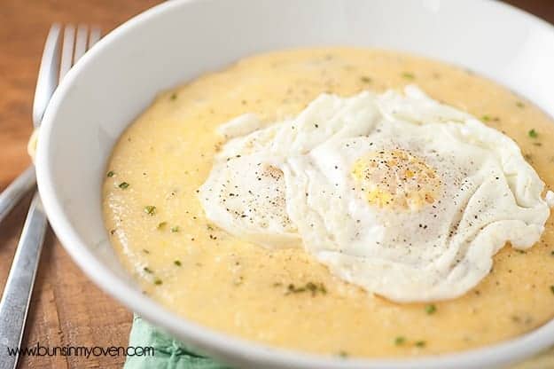 A close up of a bowl of grits with two fried eggs on top of it.