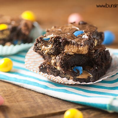 A brownie on a cloth napkin surrounded by reeses pieces.