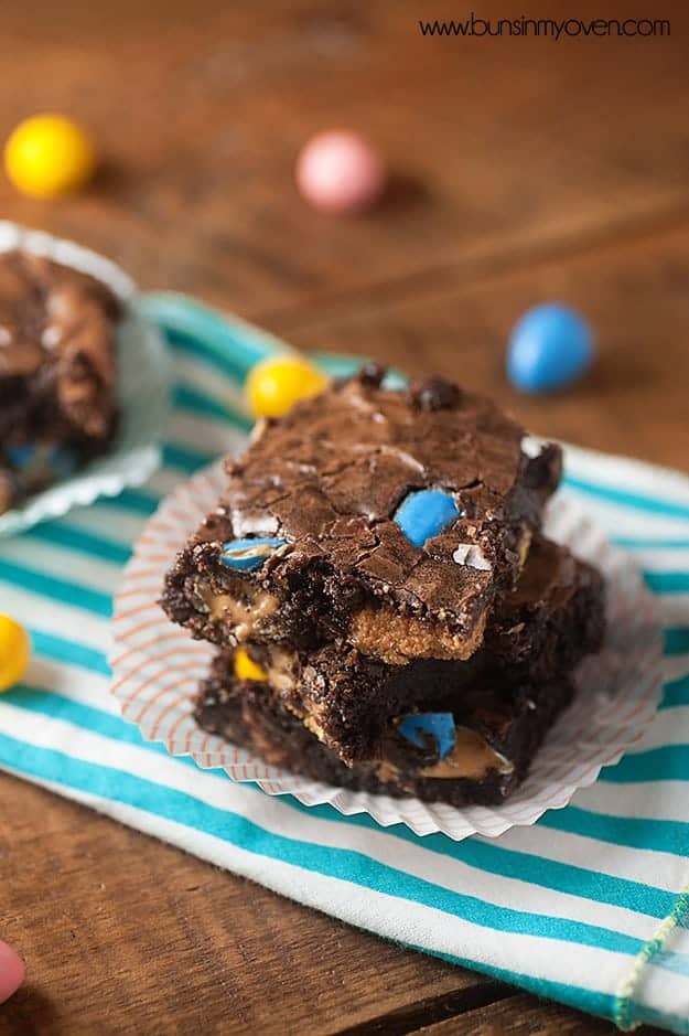 Two brownies on a paper napkin on a table surrounded by easter eggs.