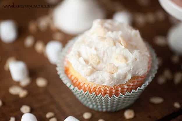 An overhead view of a cupcake with white icing on a table.