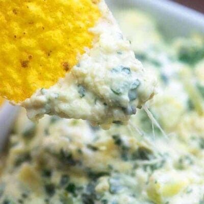 A close up of a chip with Spinach and Artichoke dip on the tip of it.