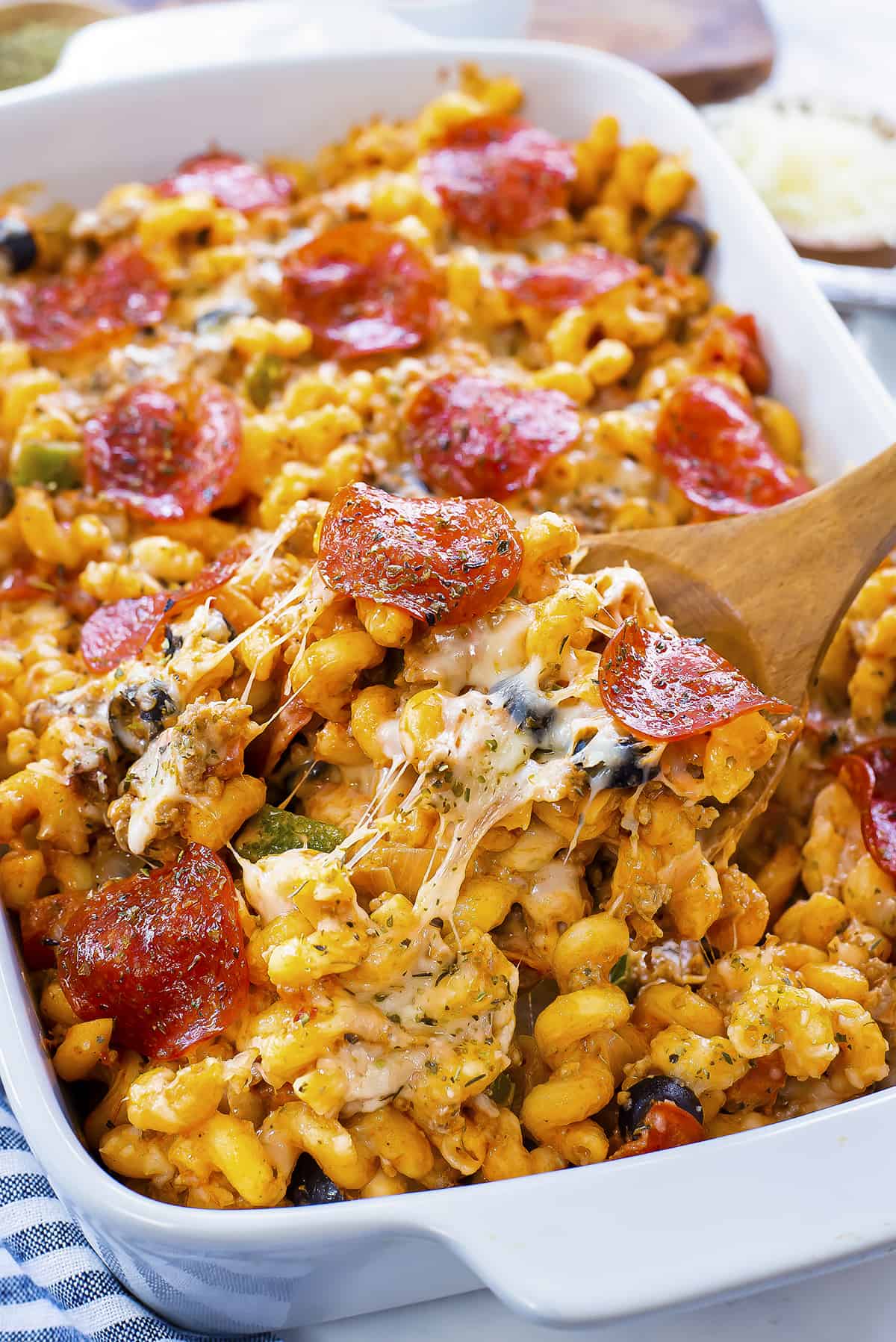 Baked cheesy pizza pasta in white dish.