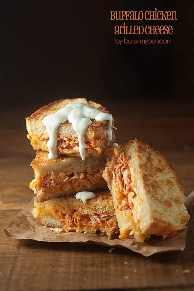 A buffalo chicken sandwich cut into four quarters on a wooden table.