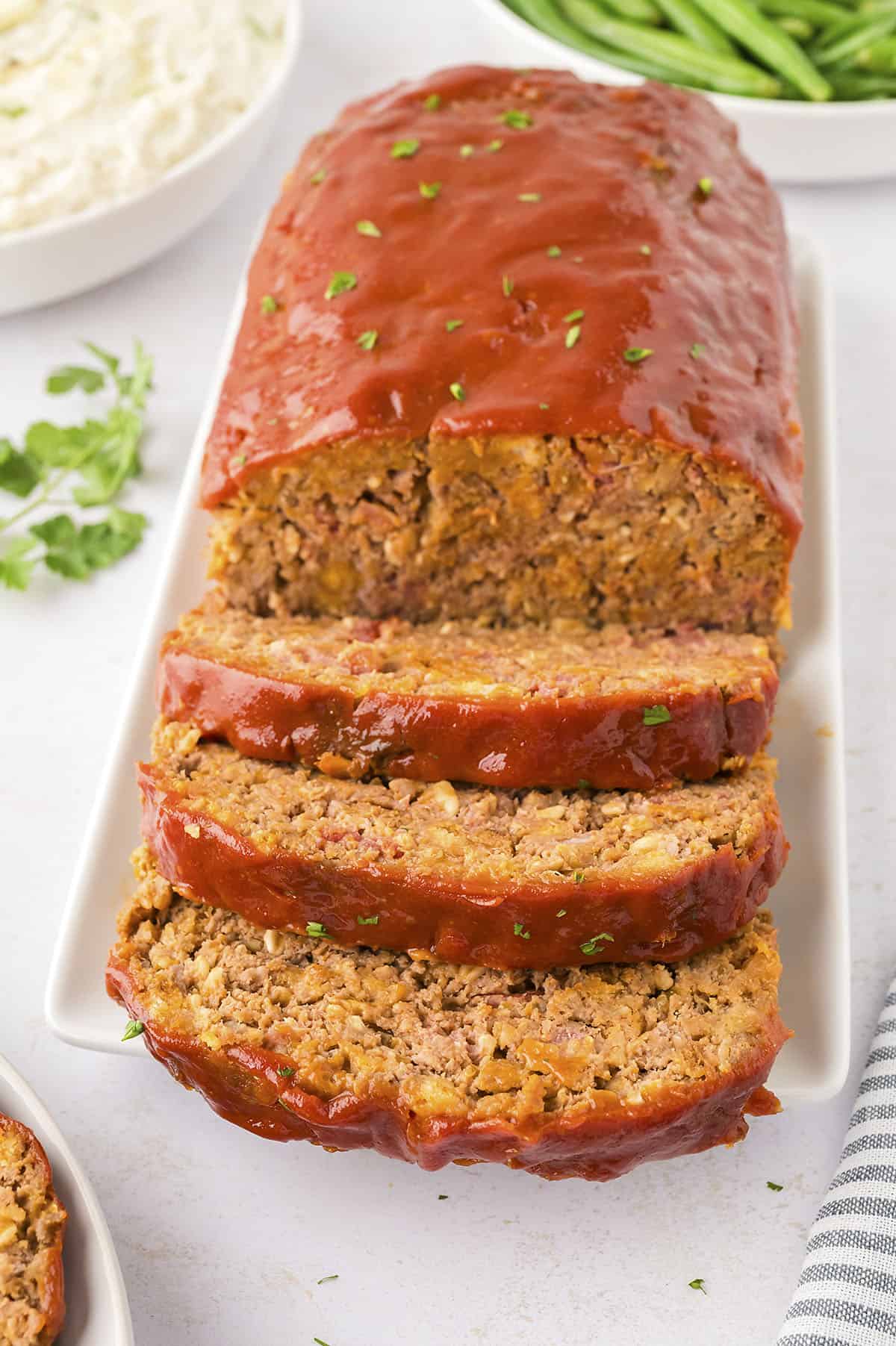 Sliced meatloaf on white platter.