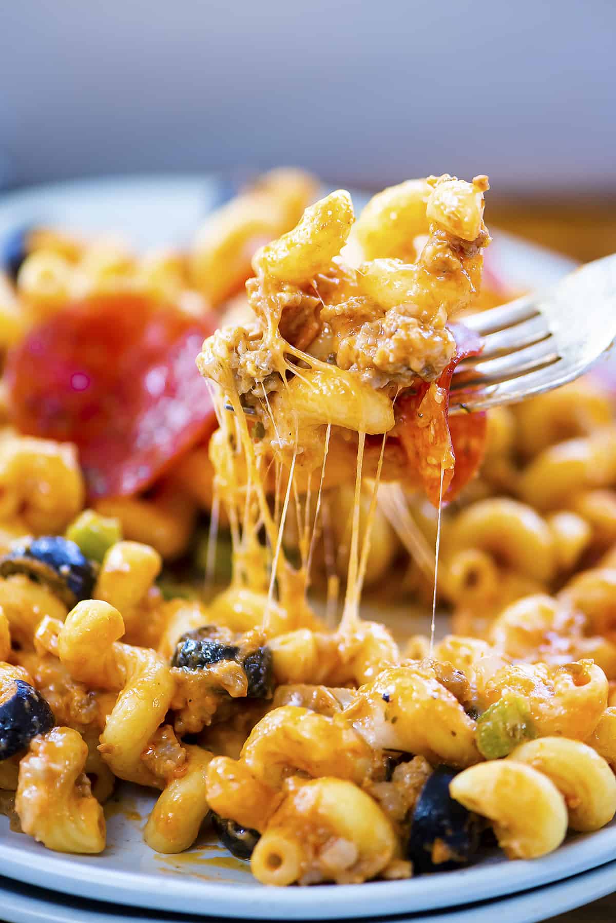 Fork digging into plate of pizza pasta.