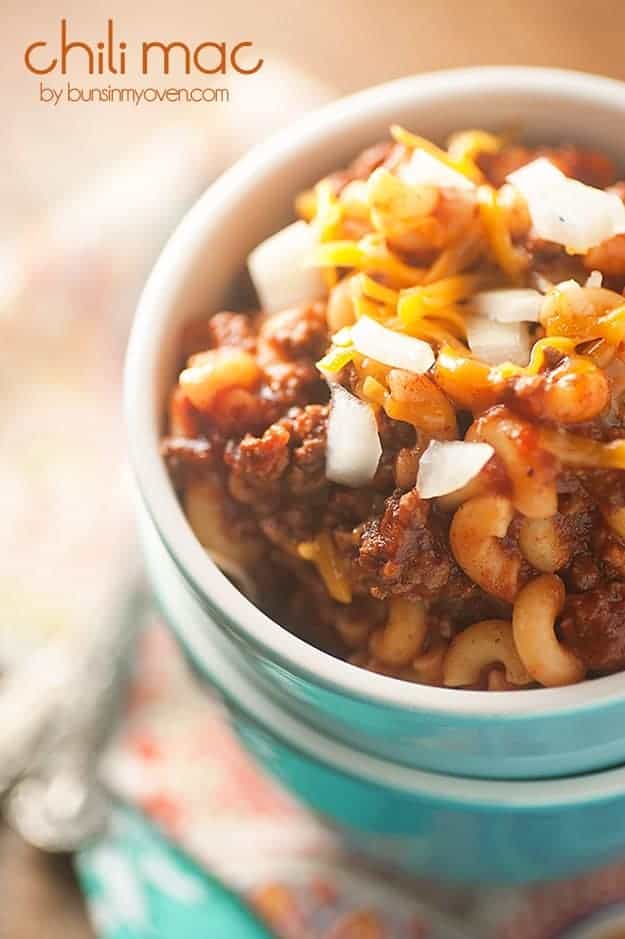 A close up of chili mac in a white soup cup.