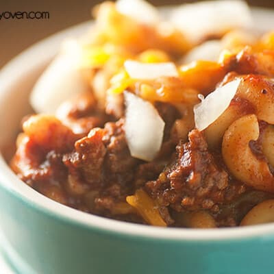 A close up of chili mac with diced onions on top.