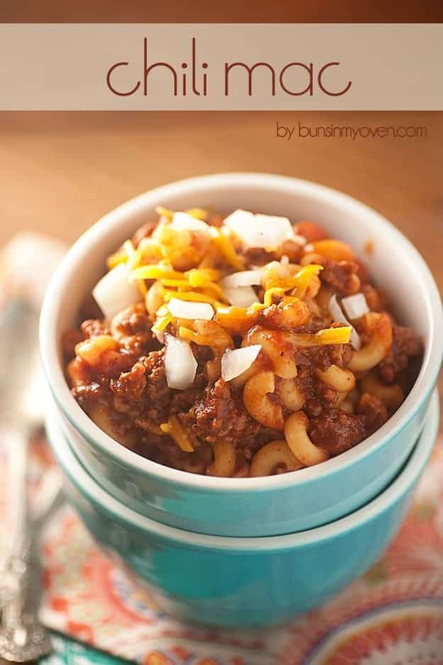 Macaroni noodles, chili, shredded cheese, and diced onions in a small white cup.