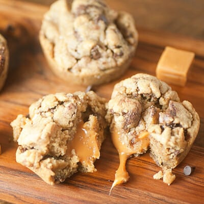 Cookie cups with melted caramel on a wooden cutting board.