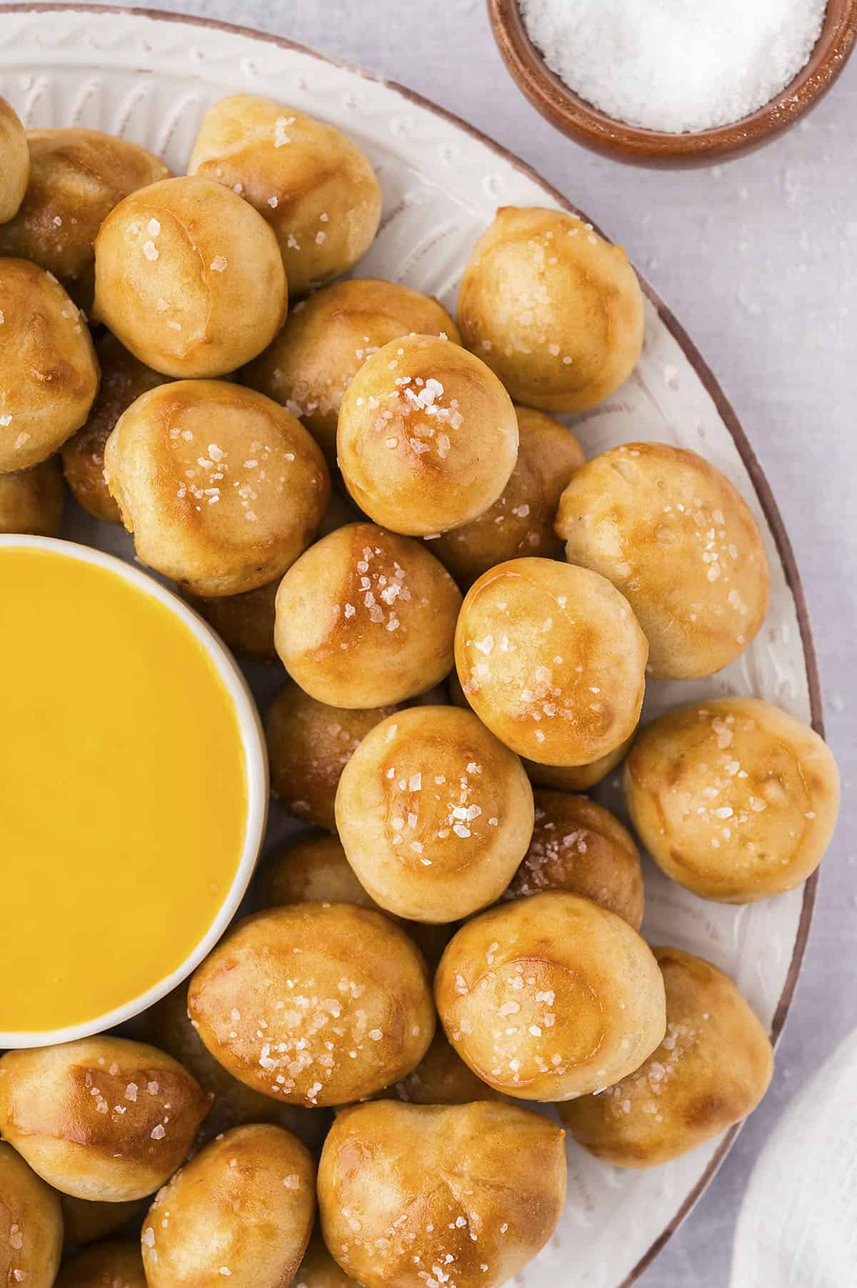 Overhead view of soft pretzel nuggets on platter with cheese sauce.