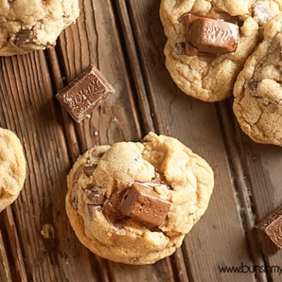 An overhead view of chunks of kit kat bars and cookies on an old wooden table.