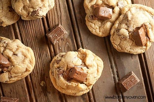 An overhead view of chunks of kit kat bars and cookies on an old wooden table.