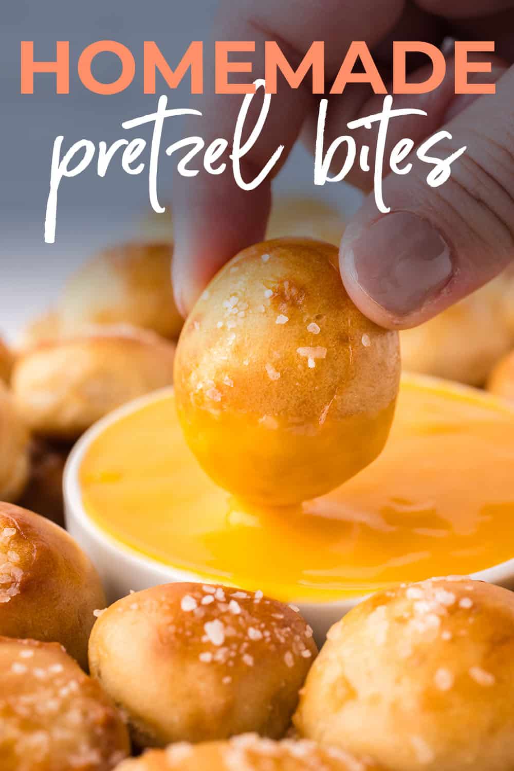 Soft pretzel bites being dunked in cheese sauce.