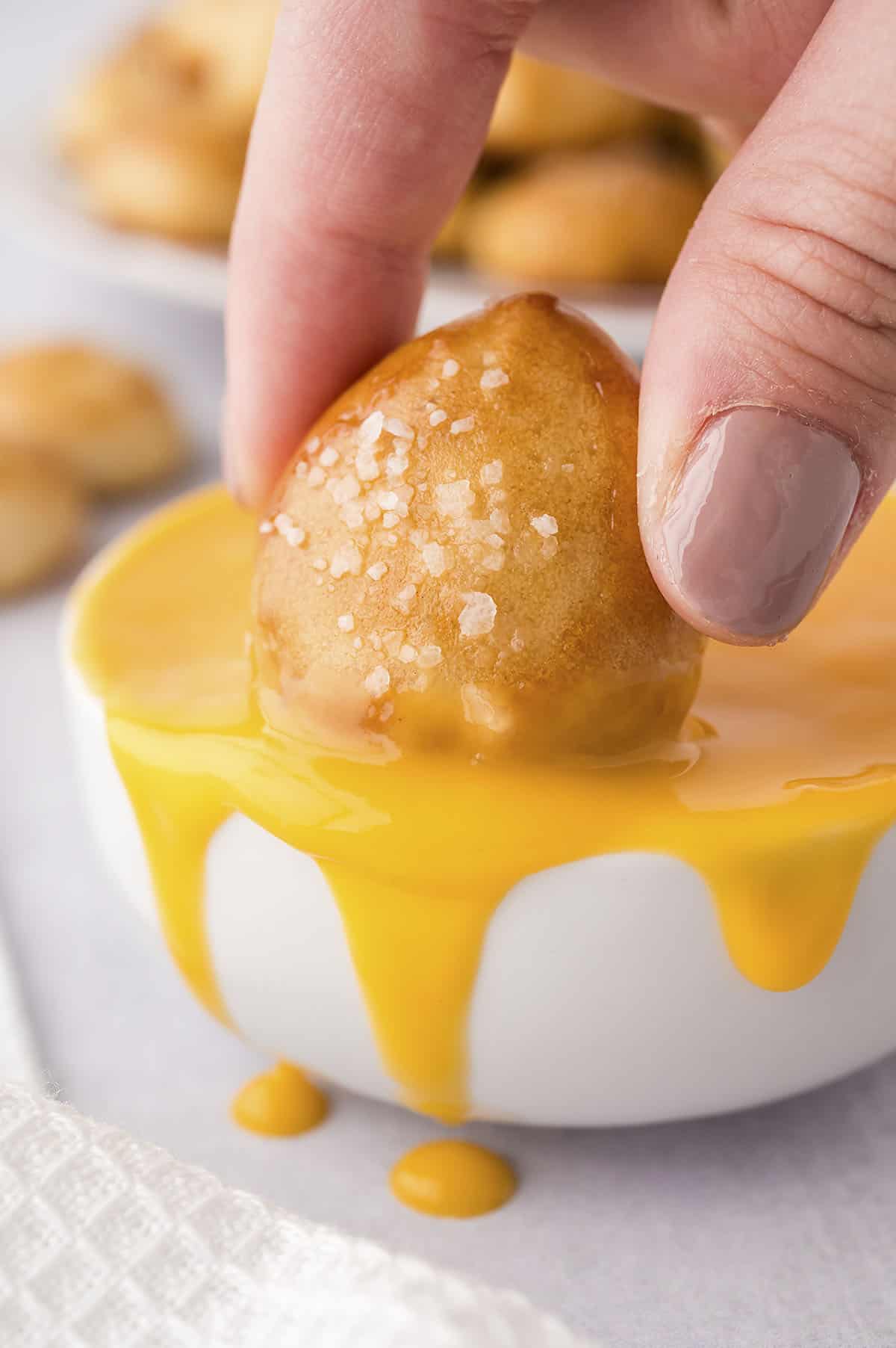 Pretzel bite being dunked into cheese dip.