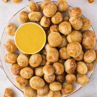 Pretzel bites on platter with cheese sauce,