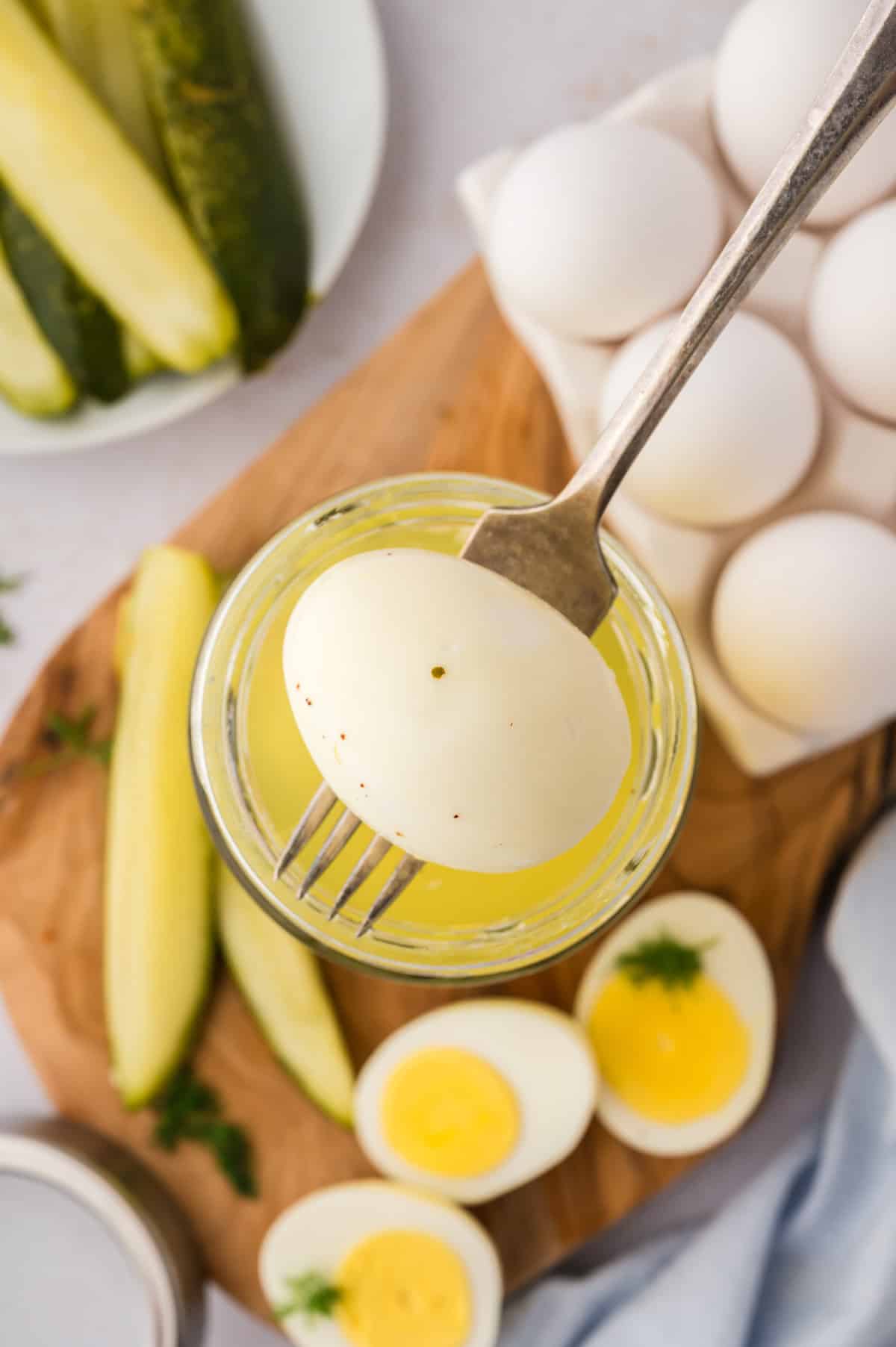Pickled egg on fork over jar.