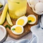 An overhead view of a hard-boiled egg cut in half on a square white plate.