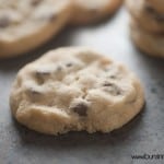 A close up of chocolate chip chookie in the foreground on a baking sheet of cookies.