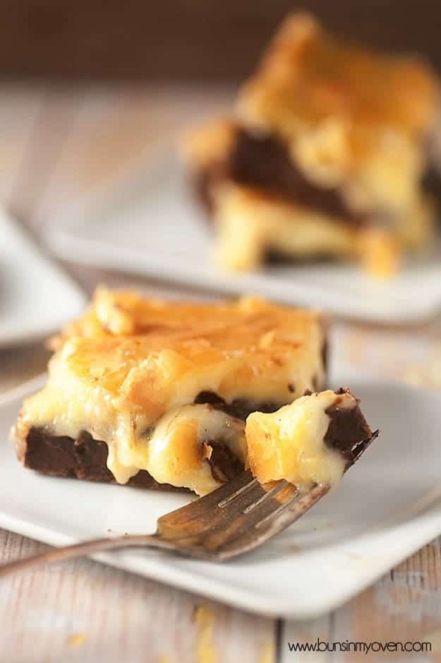 A close up of a fork with a bite of a brownie on it while resting on a white plate.