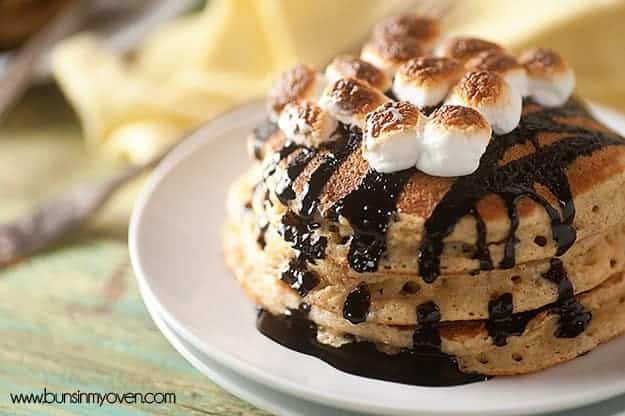 A stack of pancakes topped with chocolate syrup and toasted marshmallows.