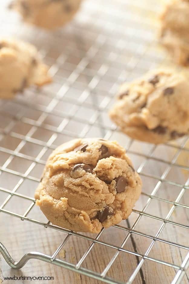 A close up of chocolate chip cookies resting on a wire cooling rack.