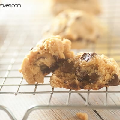 A chocolate chip cookie cooling down on a wire rack.