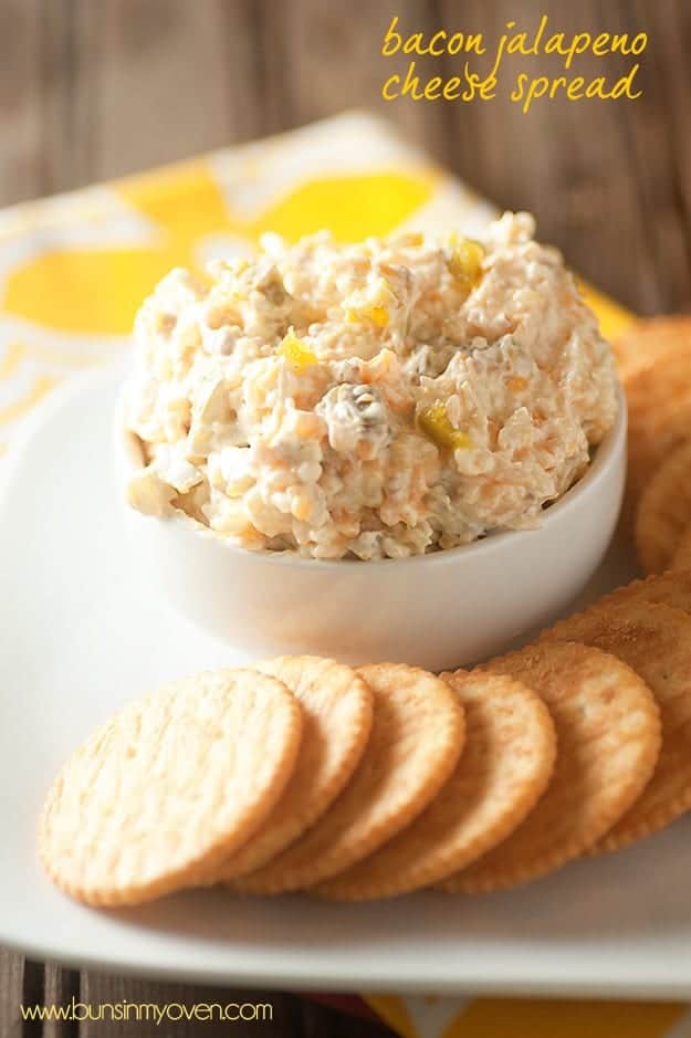 Jalapeno cheese spread in a white cup next to a row of crackers.