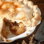 A close up of a peach pie with a slice removed.