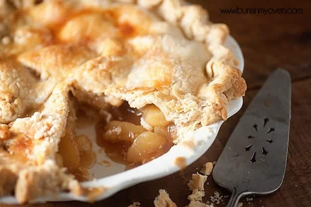 A close up of a peach pie with a slice removed.