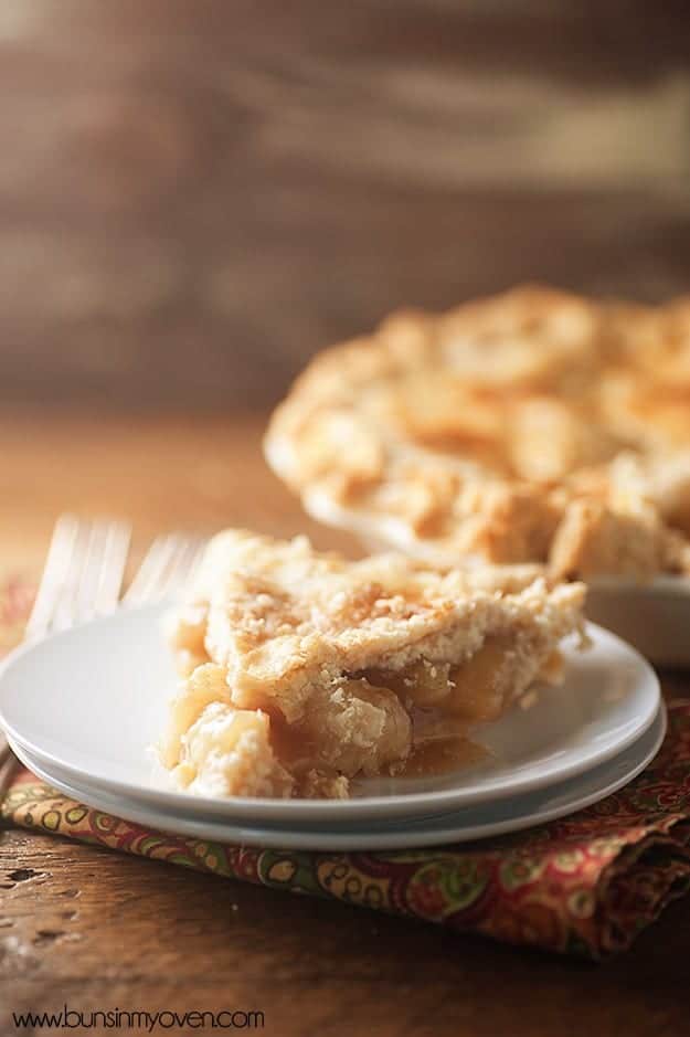 A slice of peach pie with a pie in the background.