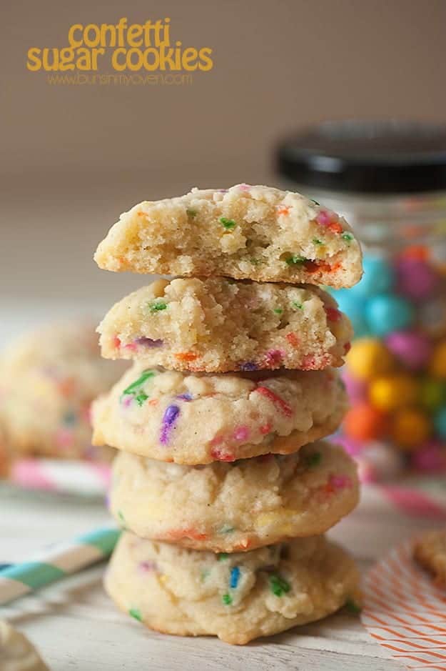 A stack of confetti sugar cookies with bites taken out of the top two cookies.