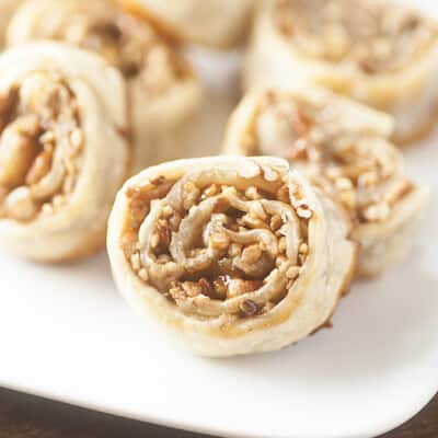 A close up of a caramel pecan pinwheel on a white plate.