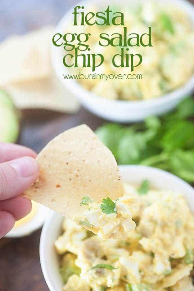 A person holding a chip dipped in egg salad dip.