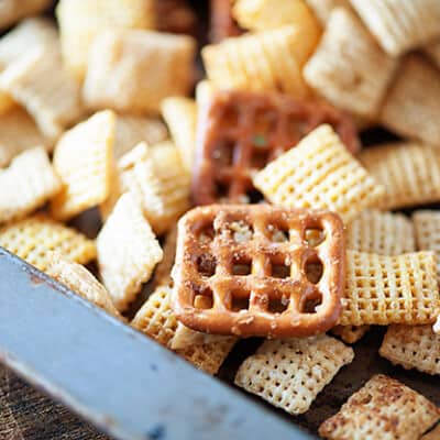 A close up of Chex cereal and a rectangle pretzel on a baking sheet.