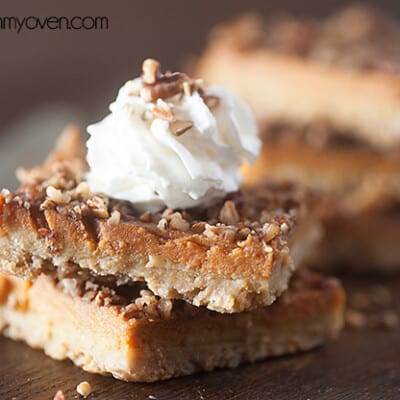 Two pumpkin pie bars topped with whipped cream.