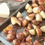 A close up of roasted potatoes in a baking sheet on a table.