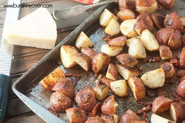 A close up of roasted potatoes in a baking sheet on a table.