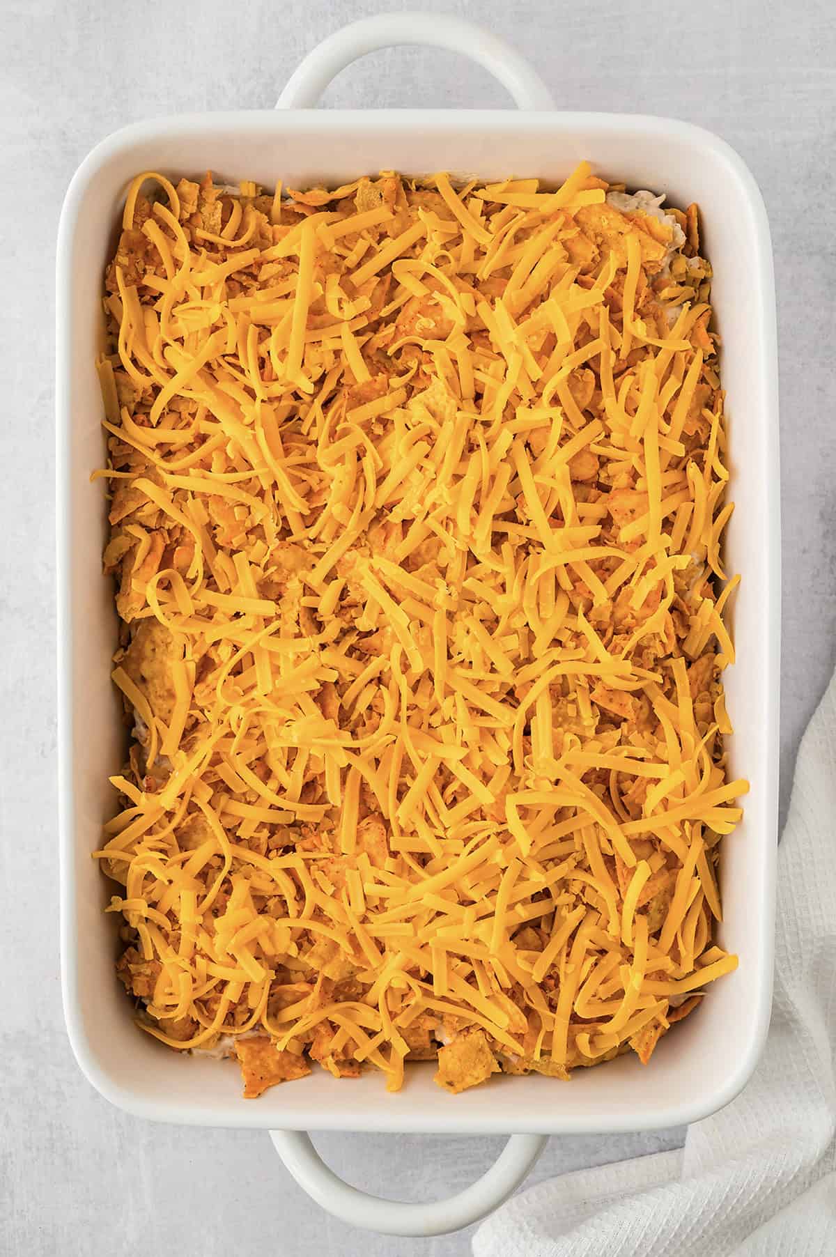 Cheese topped Dorito casserole in white dish.