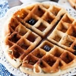 A blueberry waffle on a decorative white plate.